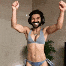 a man in a bikini and headphones is raising his hands in the air .