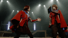 two women in red capes are dancing on stage