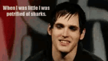 a man with black eyes is smiling with the words when i was little i was petrified of sharks