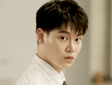 a close up of a young man 's face with a white shirt and black tie