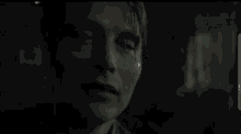 a close up of a man 's face in a dark room with a blurry background .