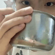 a close up of a person holding a metal cup