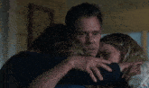 a man and two women hugging each other in a room