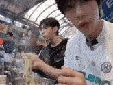 a man wearing a umbro shirt is eating noodles with chopsticks