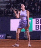 a woman in a purple skirt is holding a tennis racket on a tennis court .
