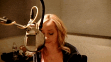 a woman sitting in front of a microphone with a bottle of water next to her
