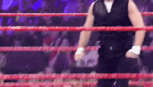 a man is standing in a boxing ring with a crowd behind him .