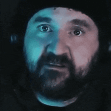 a close up of a man 's face with a beard and a hat