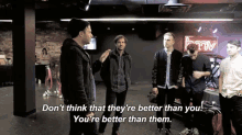 a group of men are standing in front of a hmv neon sign