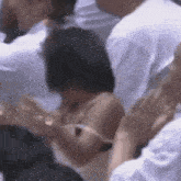 a group of people are sitting in a crowd and one of them is holding another person 's arm .