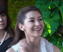 a woman in a white dress is smiling and looking at the camera
