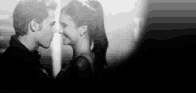 a black and white photo of a man and a woman looking at each other .