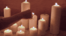 a person is lighting a candle in front of a row of lit candles