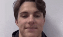 a close up of a young man 's face with a hoodie on .