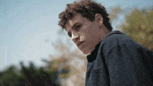 a young man with curly hair wearing a blue shirt