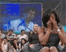 a woman is sitting in front of a group of people and crying .