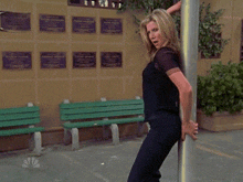 a woman stands next to a pole in front of a wall with plaques on it including one that says " memorial center "