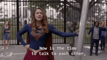 a woman in a superman costume has the words now is the time to talk to each other above her
