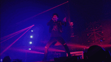 a person standing on a stage with purple lights behind them