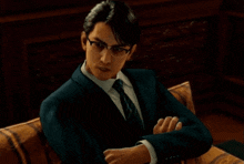 a man in a suit and tie is sitting with his arms crossed