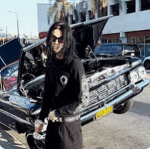a man is standing in front of a car with the hood up