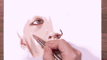 a person is drawing a woman 's face with a pencil on a piece of paper