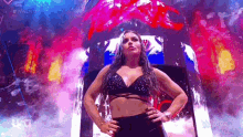 a woman is standing on a stage with her hands on her hips and a colorful background .