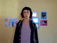 a woman with a backpack stands in front of a wall with pictures and a drawing of a man and woman