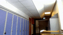 a hallway with blue lockers and a green exit sign