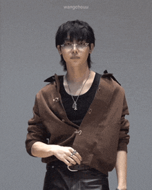 a man wearing glasses and a brown jacket has wangchouu written on the bottom