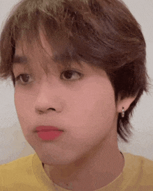 a close up of a person 's face with a yellow shirt on