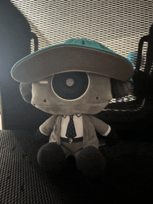 a stuffed animal wearing a hat and a tie with the letter e on it