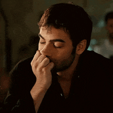 a man with a beard is covering his face with his hand
