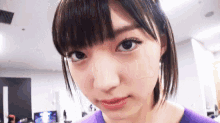 a close up of a woman 's face with a purple shirt on .