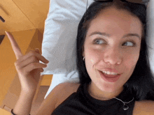 a woman laying on a bed pointing up