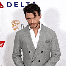 a man in a grey suit stands in front of a delta logo