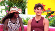 a woman wearing a cowboy hat sits next to a man in a tank top