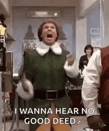 a man in a green elf costume is standing in a room with his mouth open and shouting .
