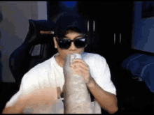 a man wearing sunglasses and a hat drinks from a can