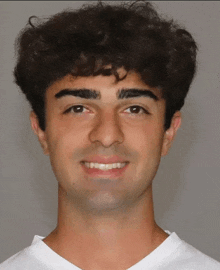a young man with curly hair smiles for the camera