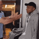 a man in a hat is shaking hands with another man in a gray jacket
