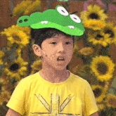 a young boy wearing a yellow shirt and a crocodile hat