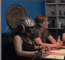 a woman wearing a helmet and goggles is sitting at a table with a man .