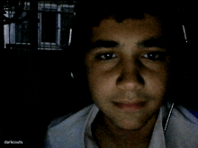 a young man 's face is shown in a dark room with the words darkscouts written on the bottom