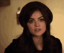 a woman wearing a burgundy hat is making a funny face .