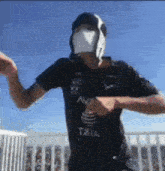 a man wearing a mask and a black shirt is dancing on a balcony .