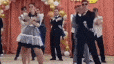 a group of people are dancing on a stage in a room .