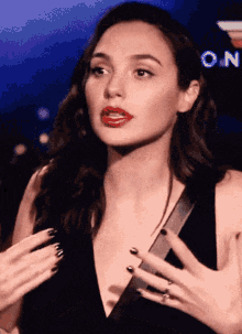a woman in a black dress with red lips and black nail polish