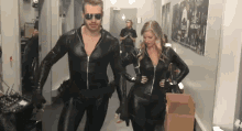 a man and a woman in black leather costumes are walking down a hallway ..