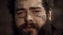 a man with a beard has many tattoos on his face including one that says always